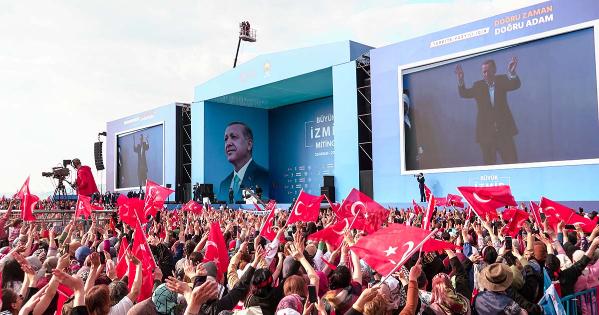 A crowd waving the Turkish flag watches as President Recep Tayyip Erdogan walks on stage at a rally