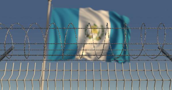 Guatemalan flag behind fence topped with razor wire