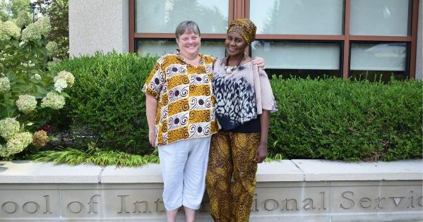 Susan Shepler and Aisha Ibrahim stand smiling in front of the SIS building.