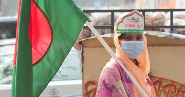 A woman holds the flag of Bangladesh over her shoulder.