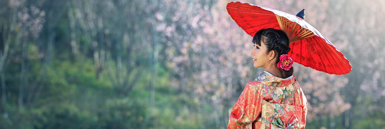 Japanese girl wearing decorated kimono poses with a paper parasol