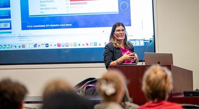 Professor Maria de Jesus lectures in front of a class.
