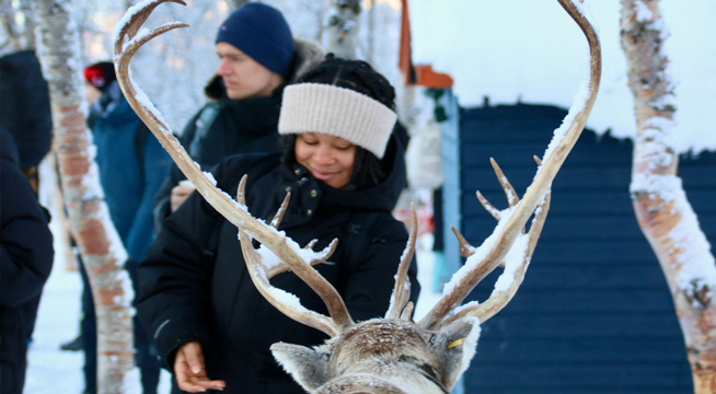 A student feeds a reindeer on a snowy day.