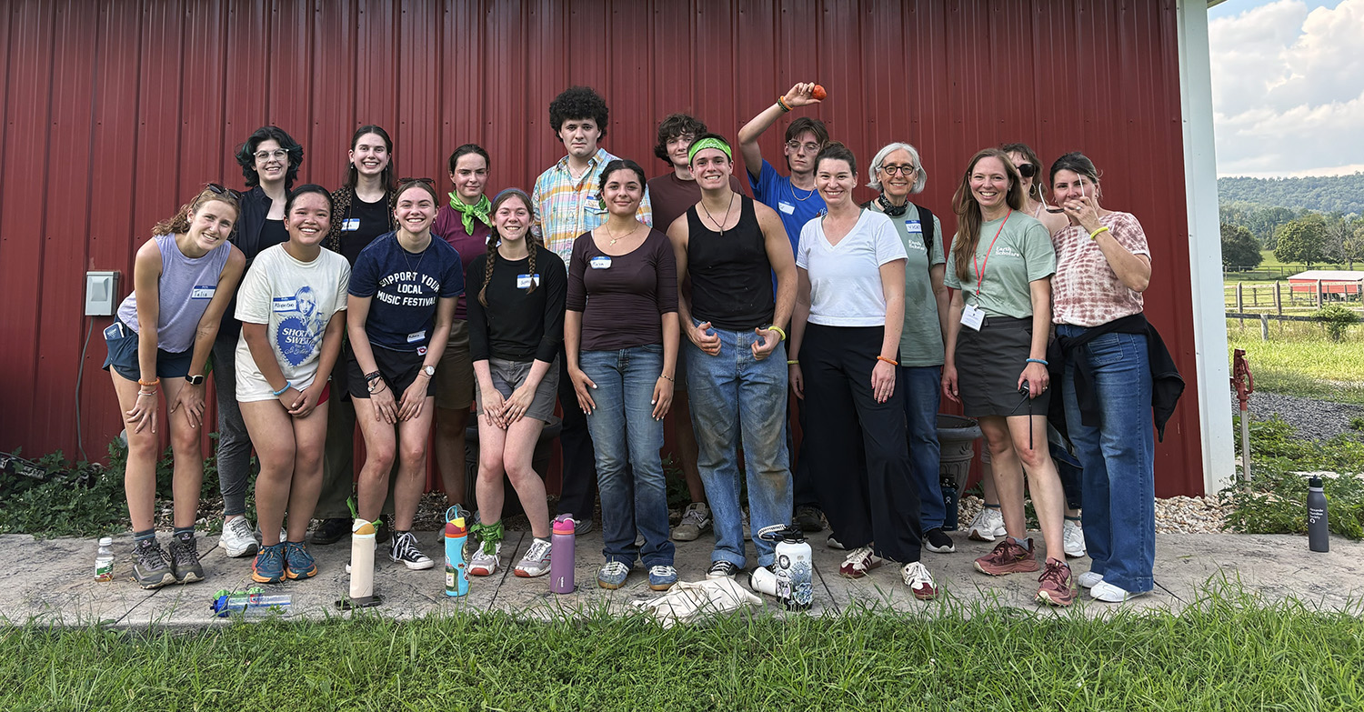 Smiling Earth Scholars pose for a group photo in front of a red barn.