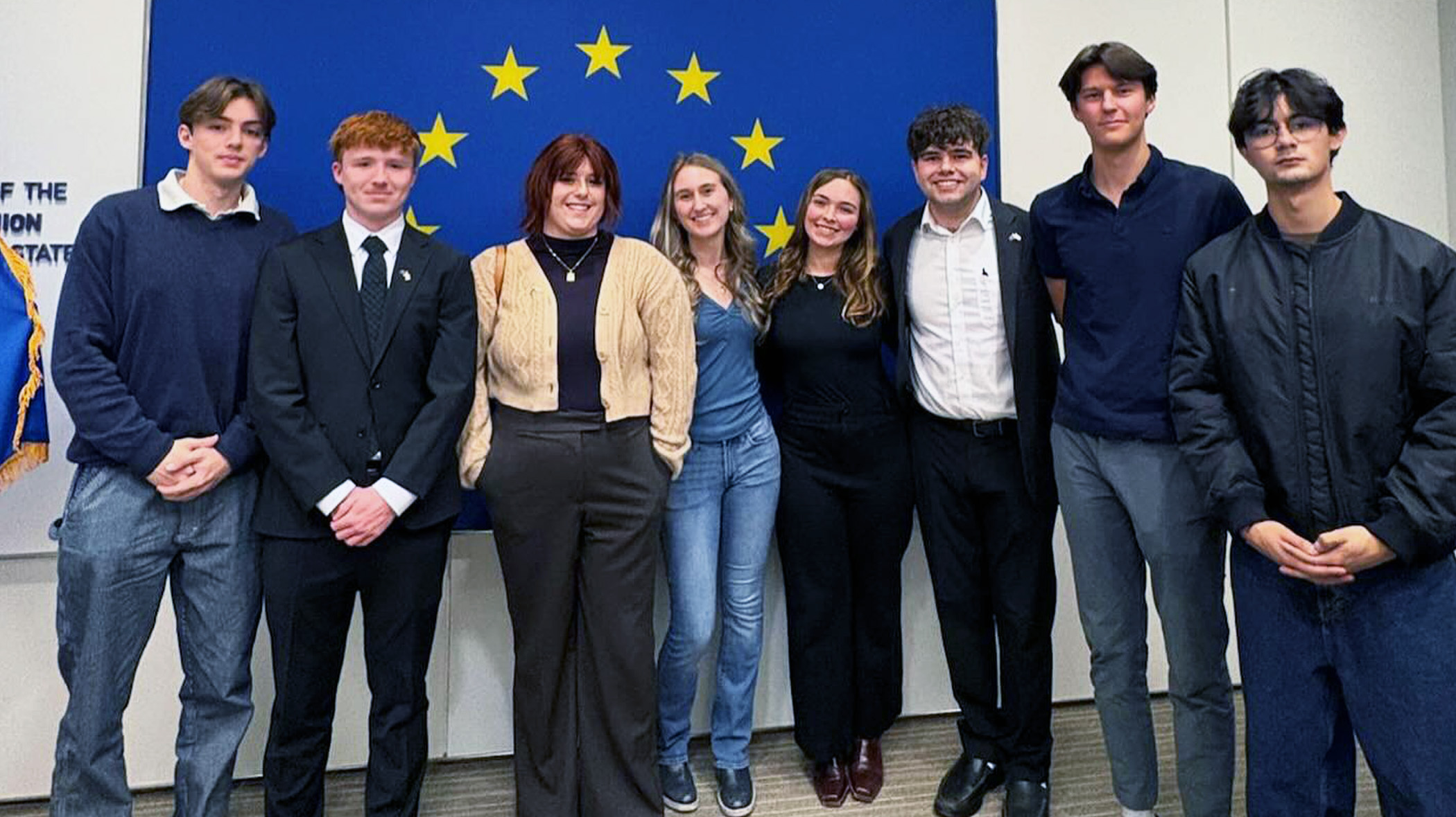 Students stand in front of the European Union flag at the headquarters of the Delegation of the European Union to the U.S.