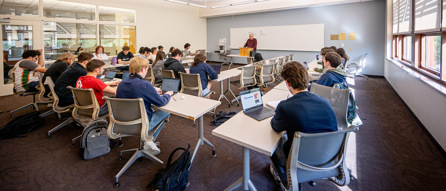 SIS students listen to a lecture and take notes in a classroom.