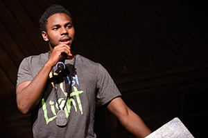 A young man speaking into a microphone on stage