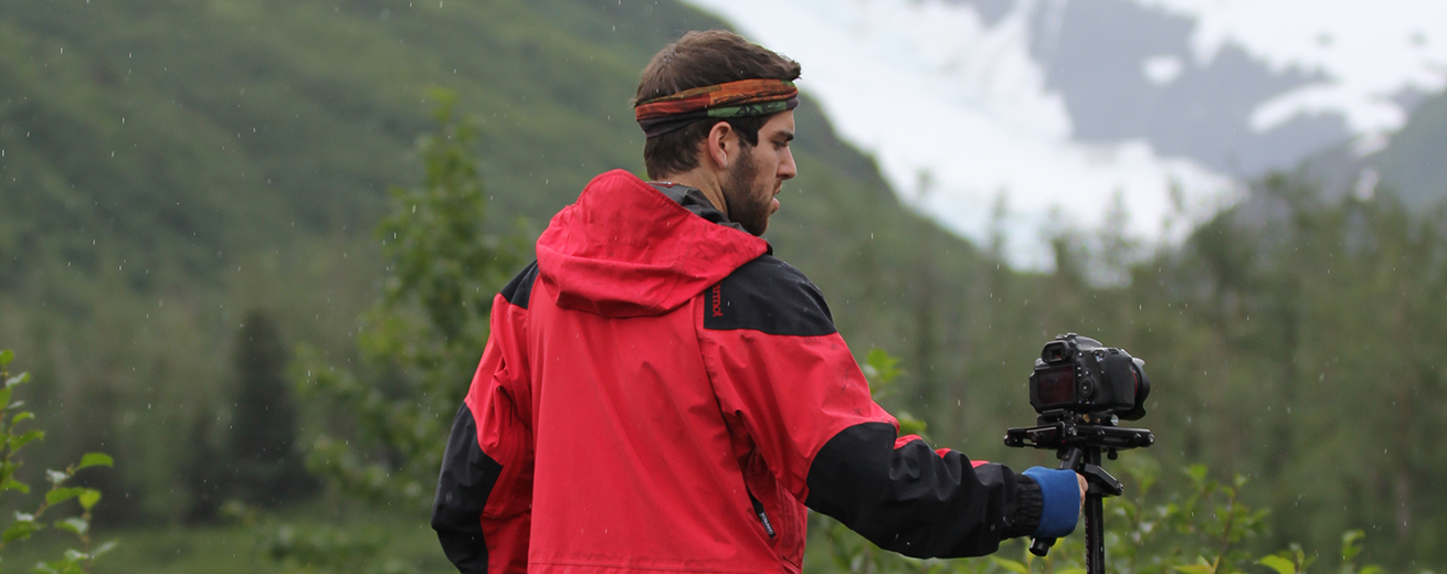 Man standing in front of a mountain holding a camera