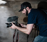 Man hunkered in cave with camera