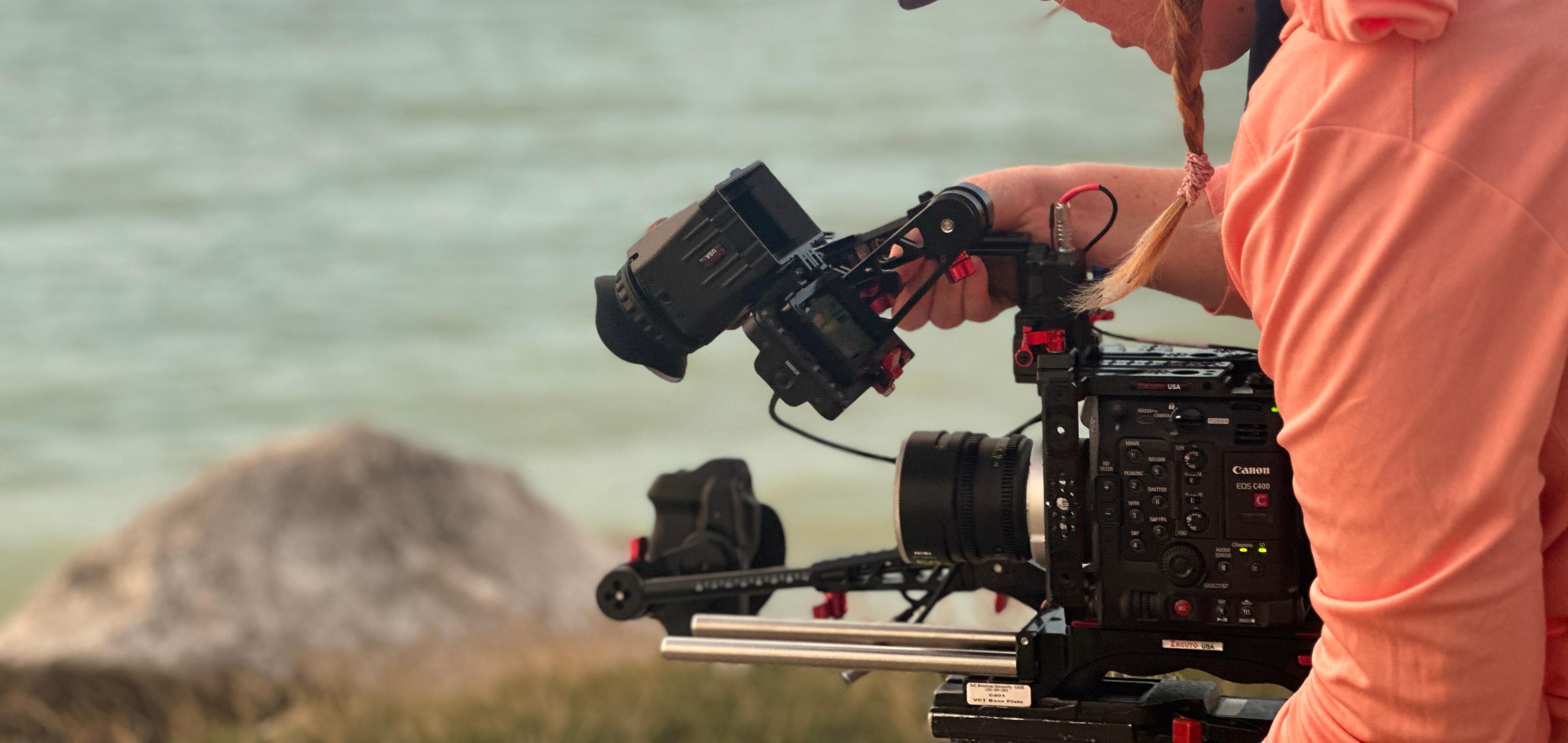 Student filming on a beach for an environmental documentary.