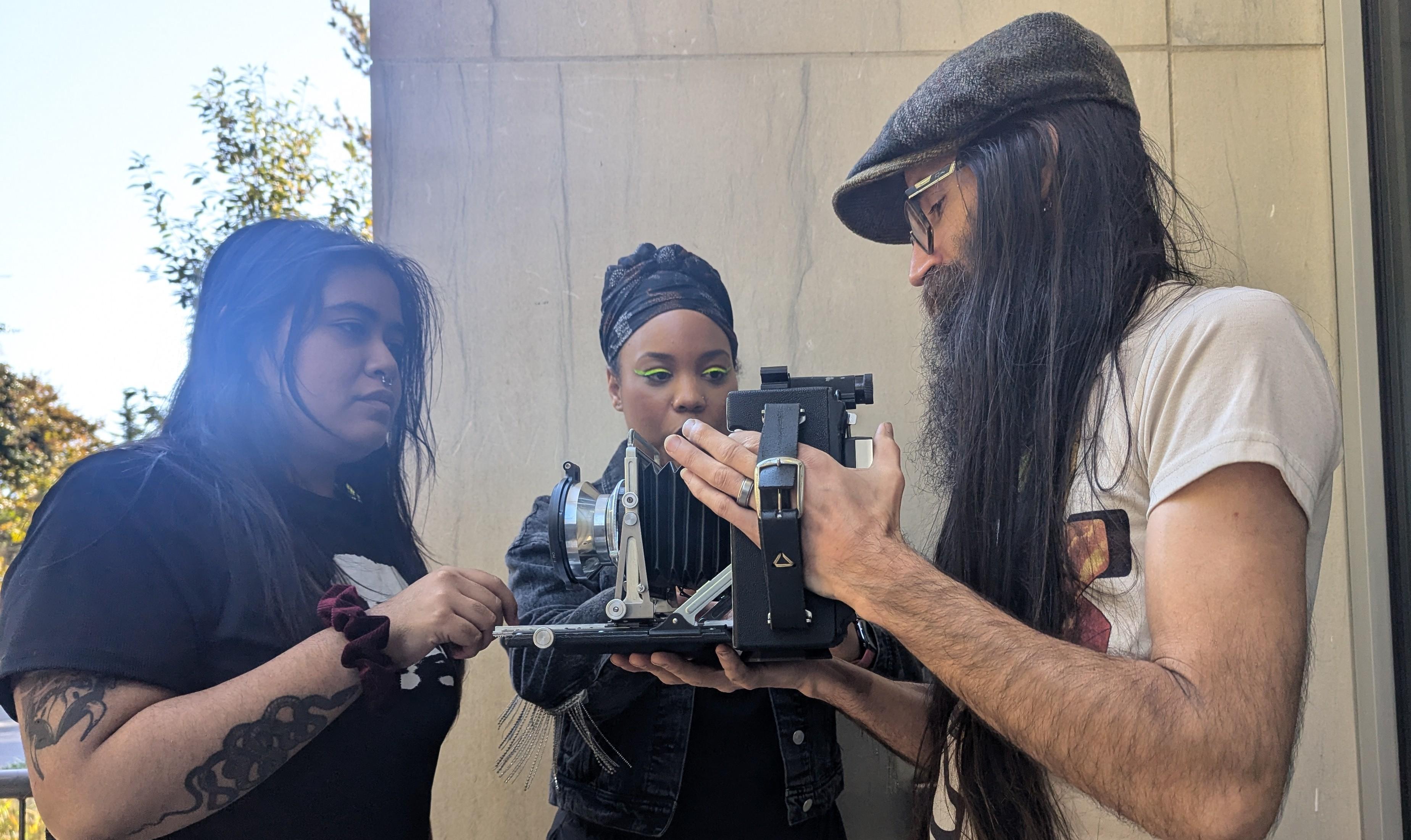 A professor is showing two students how a camera works.