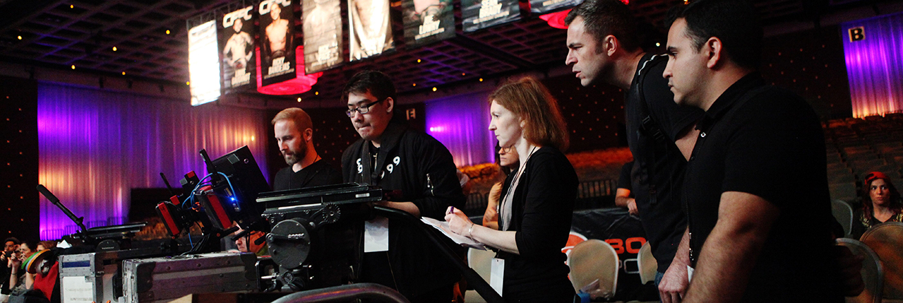 Claudia Myers working with a series of students in front of a row of computer screens and cameras