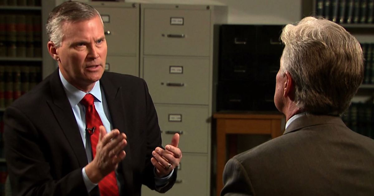 Reporter Chris Halsne interviews someone with their back to the camera