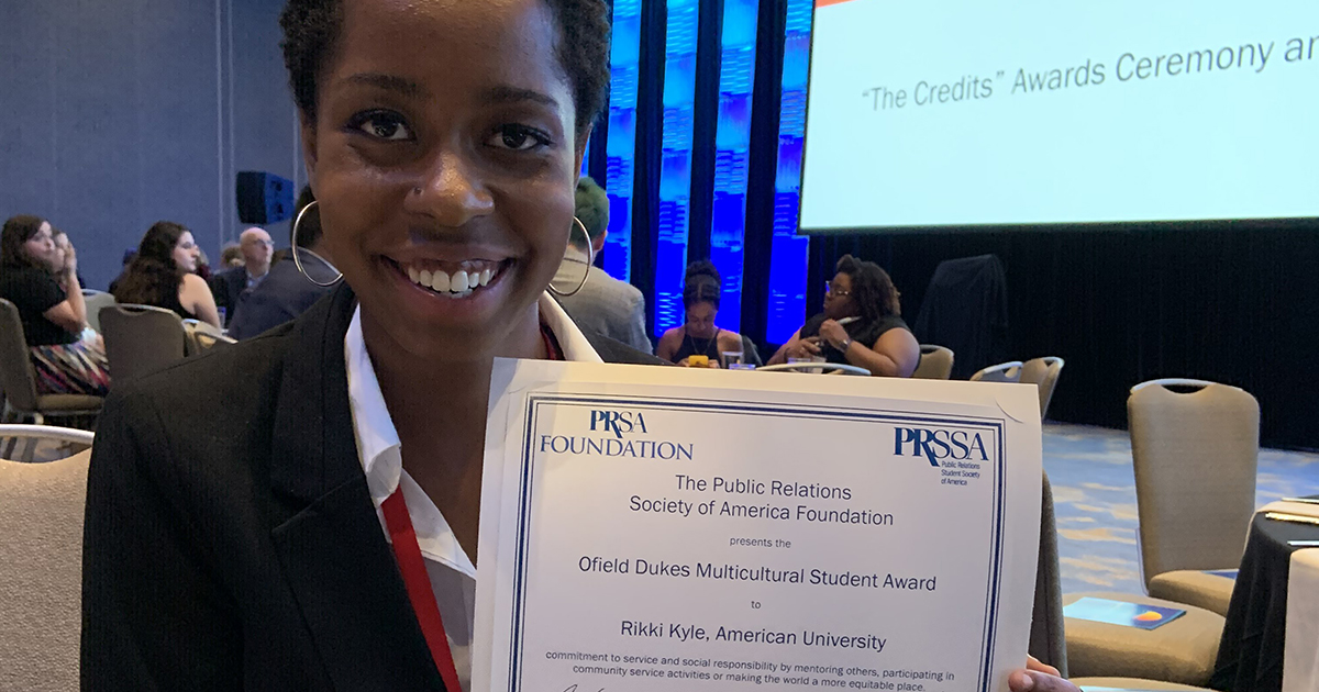 Rikki Kyle holding up a certificate at an award ceremony 