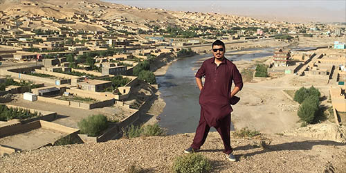 Ali Latifi standing on a hillside above a river