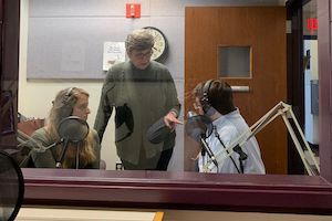 Jill Olmstead standing over two students in an audio recording studio 