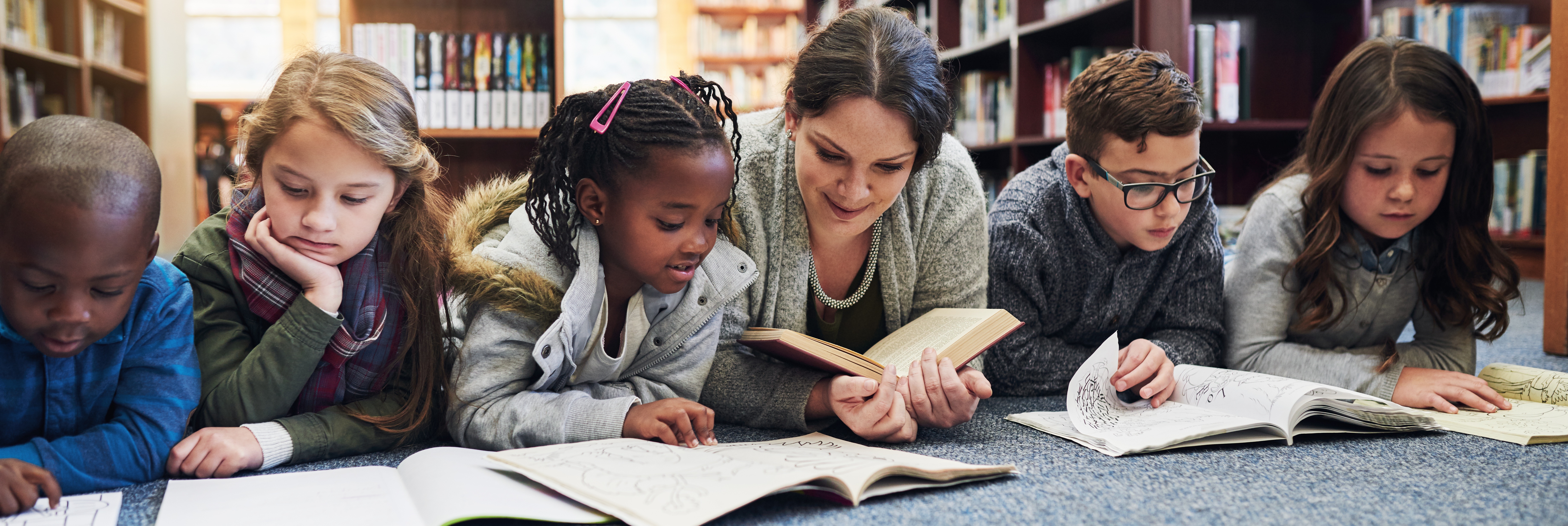 Students reading with teacher in library