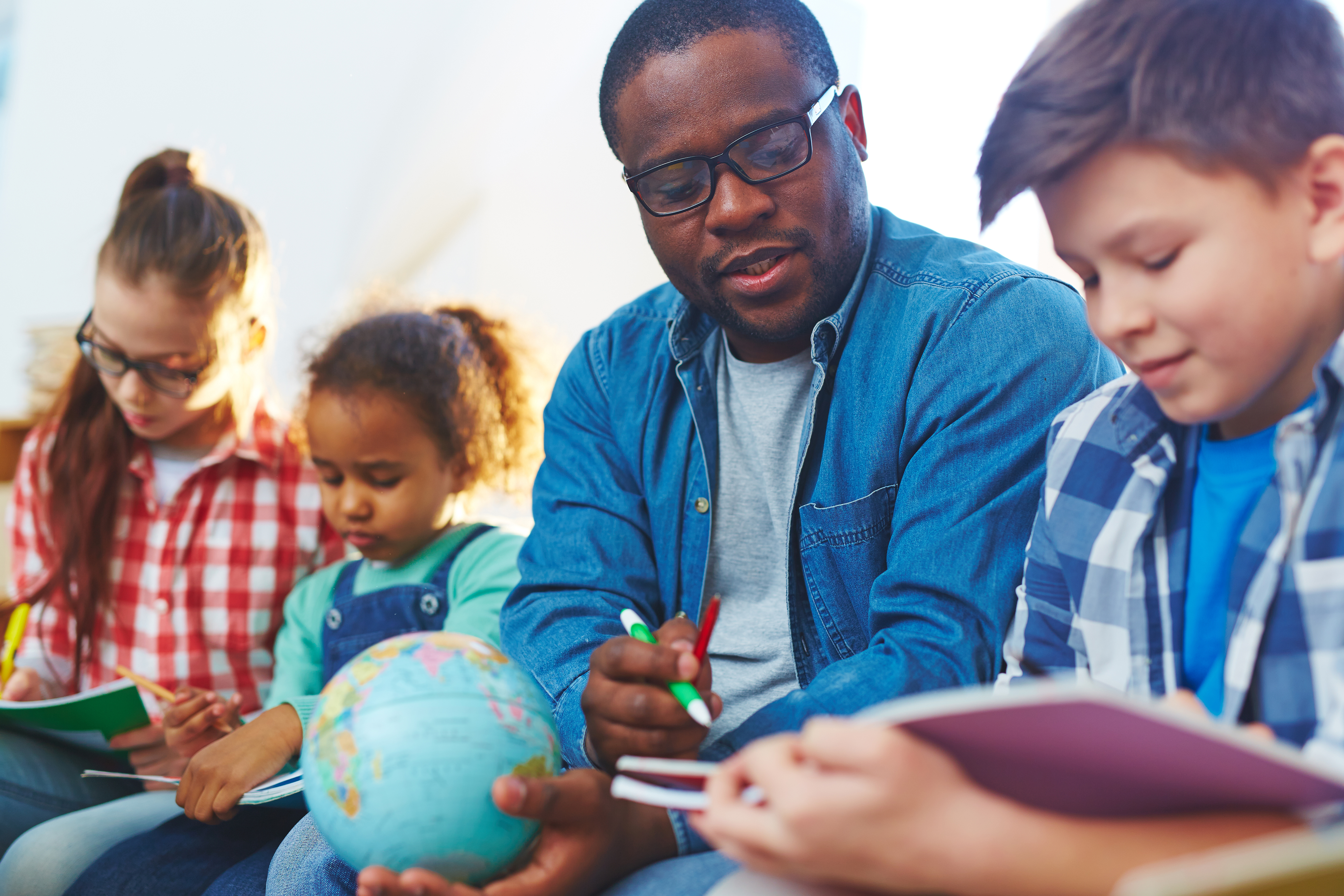 Teacher reaching with kids and globe