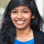 Janani Shankaran, an Asian woman with long dark hair wearing a blazer and blue shirt smiles at the camera