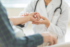 Doctor examining hand of patient.