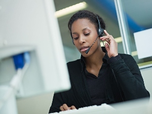 Woman at computer with headset.