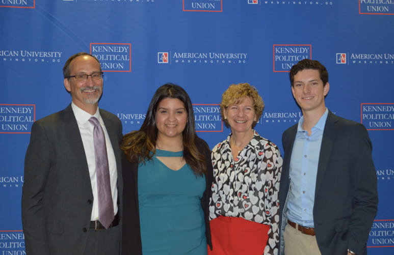 Three people stand together at event with Dr. Sue Desmond-Hellmann.