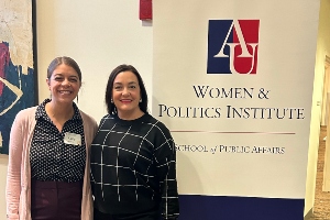 two women standing beside a banner