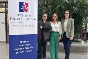three women standing next to a banner