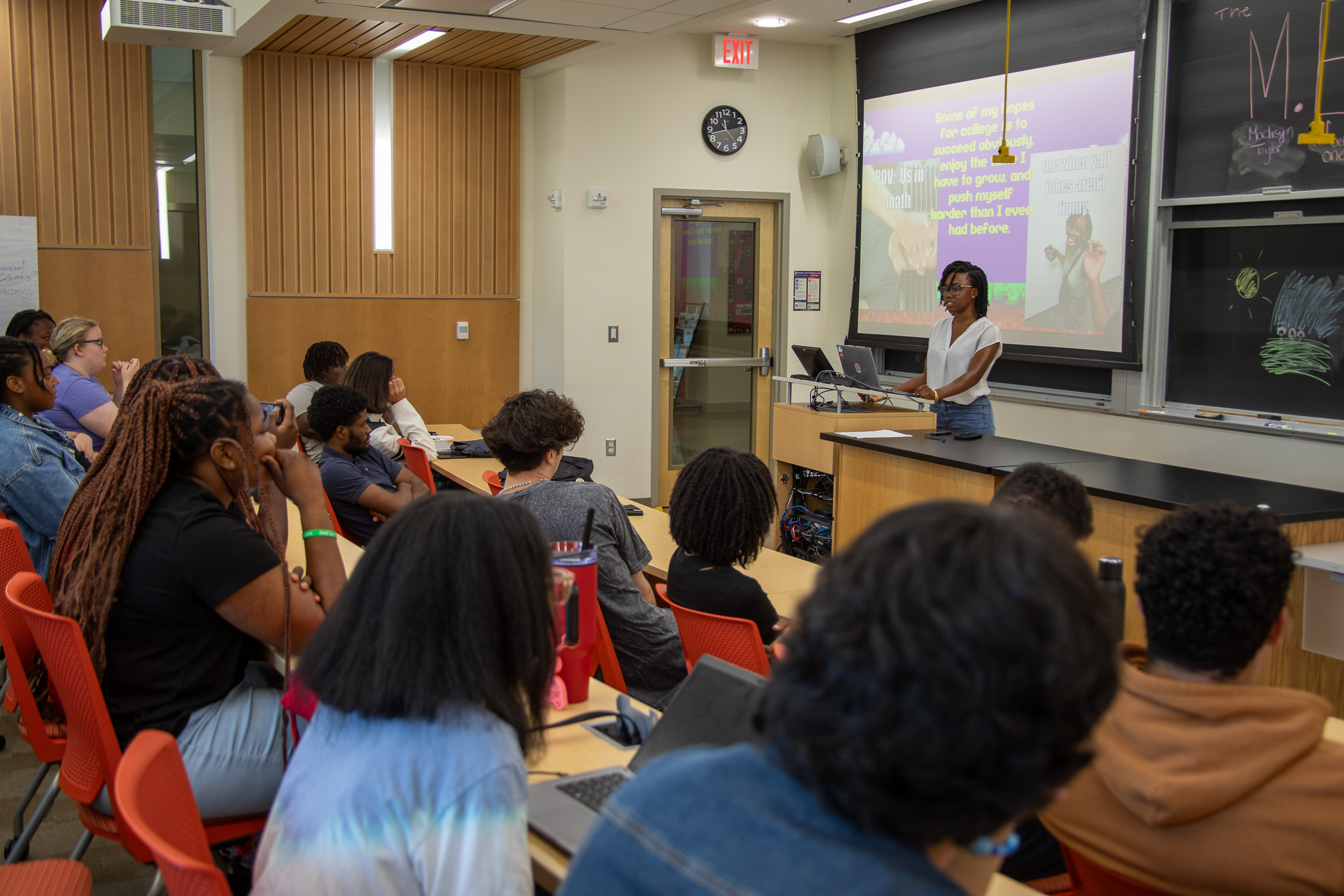 A student presents to their peers in a lecture hall.
