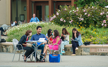 Students talking at a table outside on AU campus