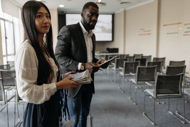 Two professionals hold notepads in a modern conference room setting