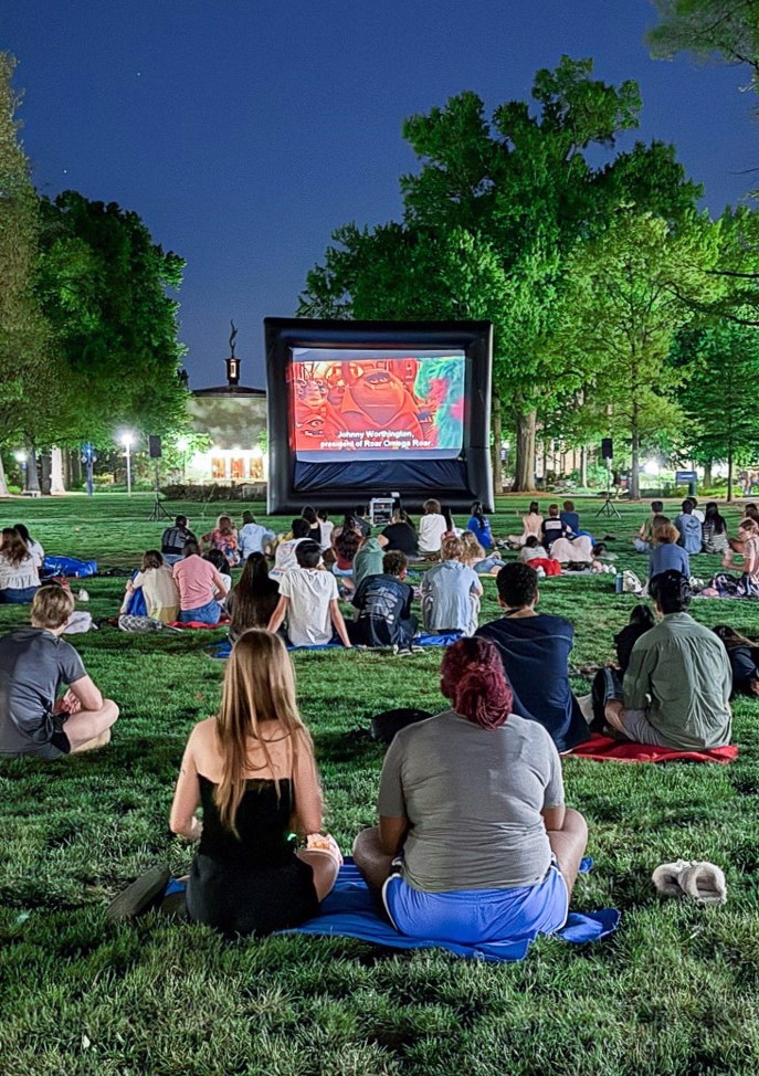 Group of students enjoying an outdoor movie night on the quad.