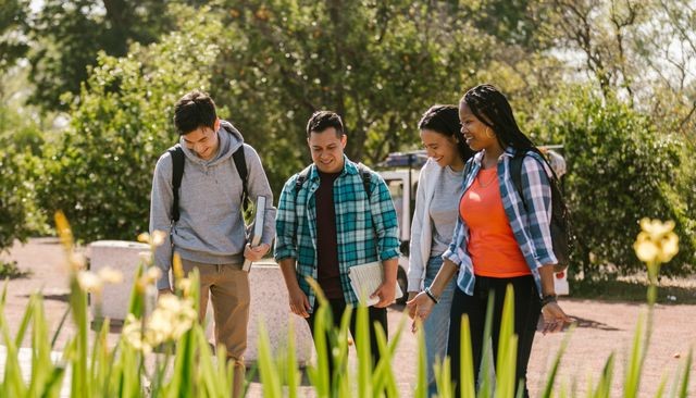 A diverse group of college students walking outdoors, enjoying each other's company and smiling