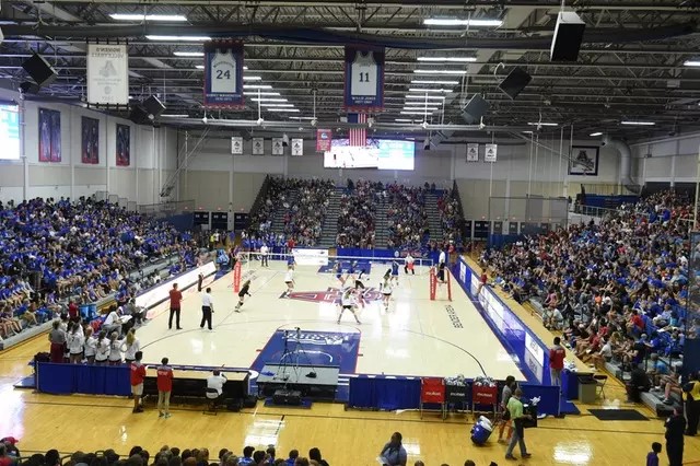 crowded arena with womens volleyball game in the middle