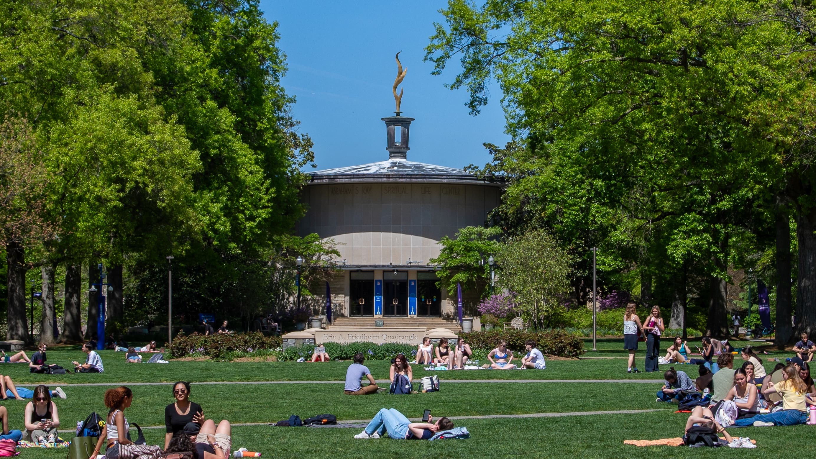 The front of the Kay Spiritual Life Center Buildings on a spring day with students sitting on the quad in front of the building.