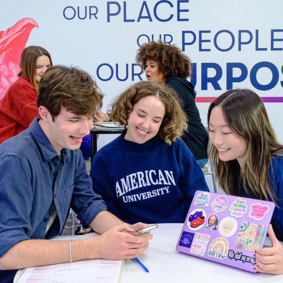 Three students interacting over a mobile home