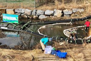 Workers clean plastics out of a river