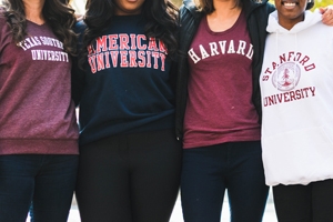 Female students wearing school sweaters from left to right: Texas University, American University, and Harvard University