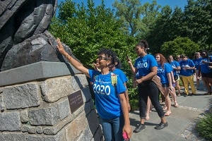 A photo of an African-American female student who is a member of AU's class of 2020.  She is touching the talons of the eagle statue for good luck.