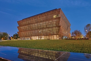 A bronze building in the shape of a crown gleams against the night sky. 