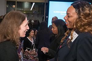 President Sylvia Burwell and an alumna shake hands.