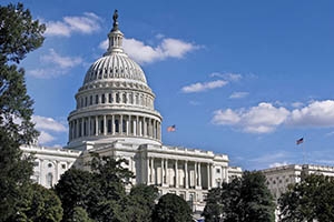 A view of the U.S. Capitol Building with a blue sky and clouds in background.