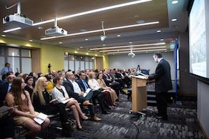 A man gives a presentation to a crowd sitting in a conference room.