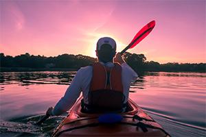 Man kayaking on the Potomac River with sunset in front of him