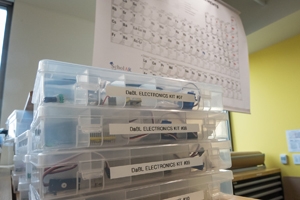 Three shelves with scientific instruments sit beneath the periodic table.