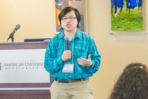 Person standing with microphone in front of a lectern.