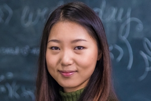 Student standing in front of blackboard with math equations in the background.