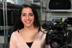 Graduate student Grace Ibrahim stands next to a camera.