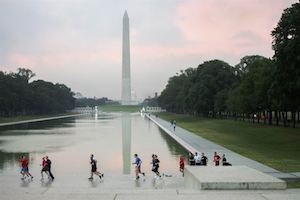 Runners on the Washington mall with Washington monument in background at sunset.