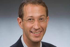 Headshot of Prof. Max Paul Friedman against a blue background.